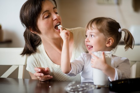 Mother and her child licking together home-made whipping creamの写真素材