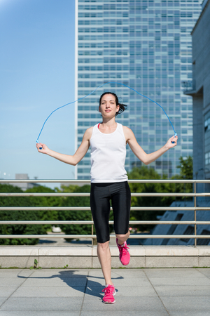 Young sport woman exercising with skipping rope in urban environmentの写真素材