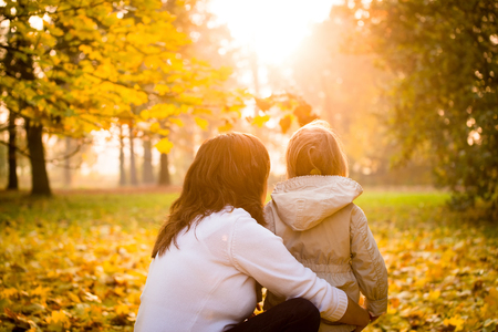 Mother and her little child watching together beautiful autumn sunsetの写真素材