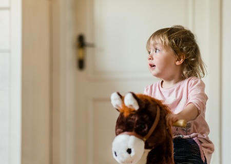 Little child playing with rocking horse at homeの写真素材