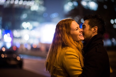 Young couple kissing and hugging outdoor in night street at christmas timeの写真素材