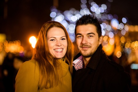 Portrait of young couple in street at night with with neon lights in background