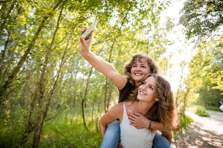 Mother and her teenager daughter  taking selfie with mobile phoneの写真素材