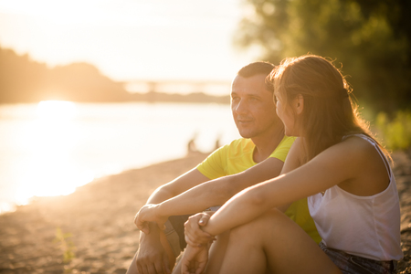 Father with his adult daughter sitting near the riverの写真素材