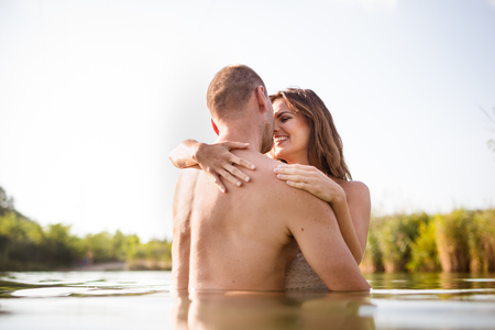 Cheerful love couple embracing in lake on a summer dayの写真素材