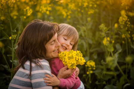Smiling woman embracing her cute daughter, outdoors.の写真素材