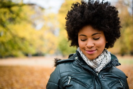 Shy young smiling woman in autumn parkの写真素材