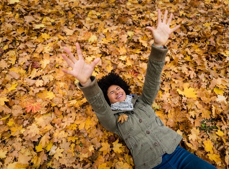 Cheerful woman lying on dry autumn leavesの写真素材