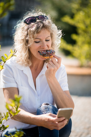 Woman bitten chocolate donut cake. Outdoor lifestyle concept.の写真素材