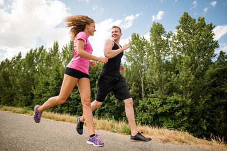 Healthy smiling fitness couple running outdoorsの写真素材