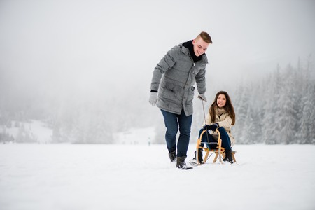 Woman being dragged on sledge by her boyfriendの写真素材