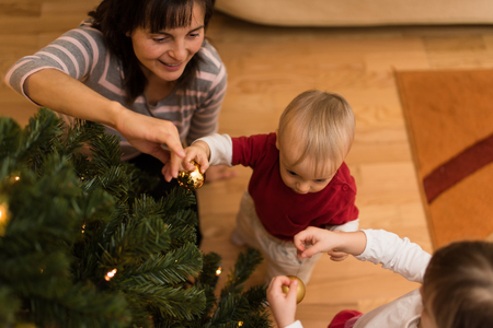 Happy family decorating christmas tree togetherの写真素材