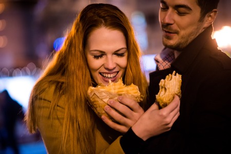 Couple having fun - eating together in streetの写真素材