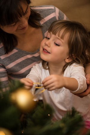 Kid decorating christmas tree with motherの写真素材