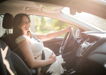 Beautiful smiling pregnant woman sitting in carの写真素材