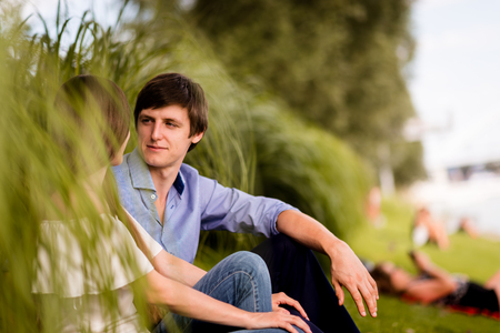 Romantic couple sitting in park - candid shotの写真素材