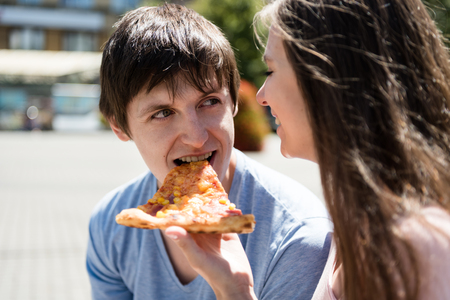 Cheerful couple sharing a pizza sliceの写真素材