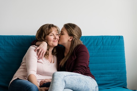 Affectionate teen daughter kissing her loving mother