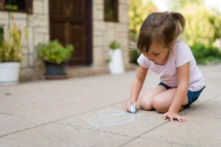 Child drawing with chalk in backyardの写真素材