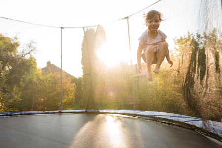 Girl child playing on trampoline in backyardの写真素材