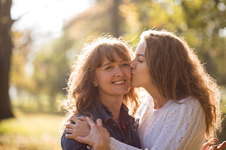 Mother being kissed by her teen daughterの写真素材