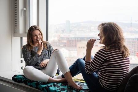 Happy teenage daughter with mother eating chocolate bar