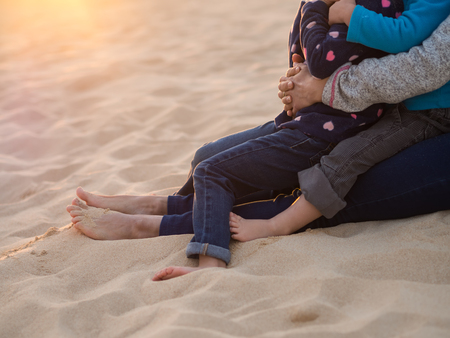 Children sitting in lap of mother, cropped image.の写真素材