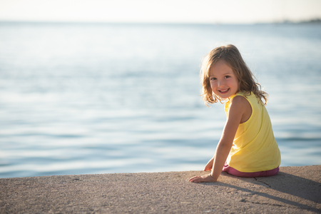 Portrait of smiling girl sitting near an ocean shoreの写真素材