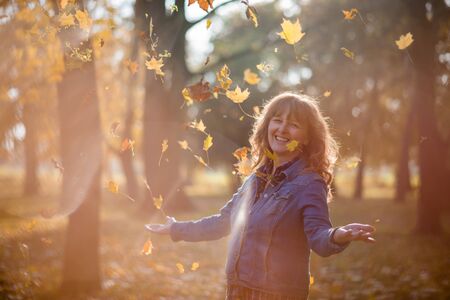 Mature woman enjoying falling colorful leavesの写真素材