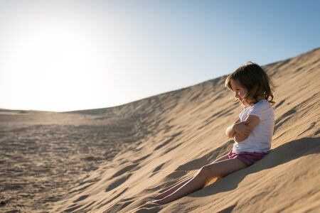 Little girl sitting and relaxing on sand duneの写真素材