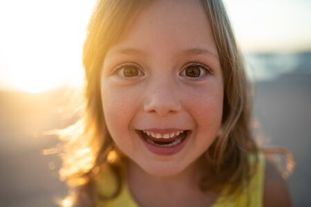 Portrait shot of cheerful little girl during sunsetの写真素材