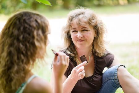 Pretty women consuming chocolate bar, outdoor shot.の写真素材
