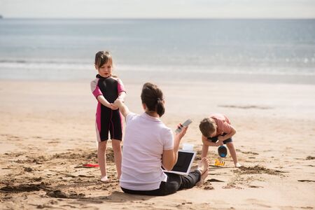 Busy mother on telephone being pulled by her daughterの写真素材