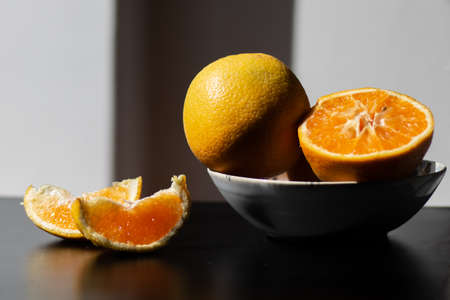 Oranges for breakfast. Healthy fruit in a plate on a table with sunshineの写真素材