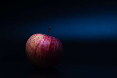 One red fresh apple on a black background. Healthy fruit and breakfast