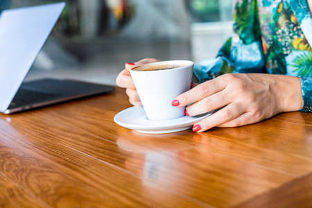 Portrait of a young woman sitting at the cafe and enjoying cup of coffee. The coffee bar is next to the train station of Lisbon, Portugal. Is a place with wooden tables and fresh tasty foodの写真素材