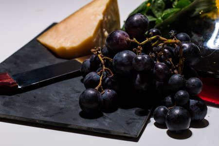 Minimal food composition of wine, grape and parmigiano (italian cheese) on a white background. Fresh...