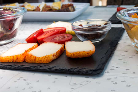 Different kinds of delicious and tasty cheese, with cherry tomatoes and isolated black greek olives....