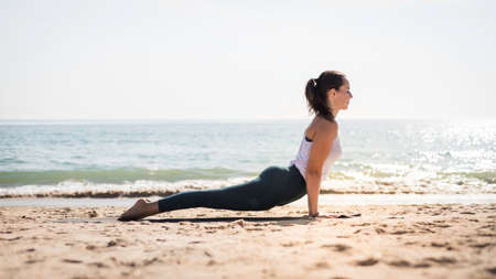 Strong Yoga teacher woman doing an intensive workout along the beach against a seamless pattern...