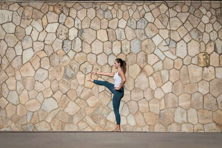 Sporty young woman doing Yoga exercises using a gym mat along the beach in Lisbon, Portugal. Playful...