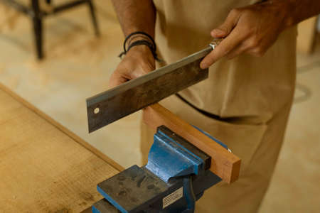 A young female carpenter working as wood designer in a small carpentry workshop. Young business...