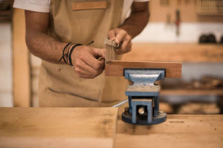 A young female carpenter working as wood designer in a small carpentry workshop. Young business woman handcrafting a piece of timber and designing new house furniture. Entrepreneurs concept lifestyle A young female carpenter working as wood designer in a small carpentry workshop. Young business woman handcrafting a piece of timber and designing new house furniture. Entrepreneurs concept lifestyle