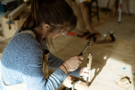 A young couple of carpenter working together in a small wood laboratory using a drill machine for timber. Couple crafting new home furniture in a carpentry workshop. young entrepreneurs concept A young couple of carpenter working together in a small wood laboratory using a drill machine for timber. Couple crafting new home furniture in a carpentry workshop. young entrepreneurs concept