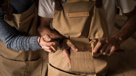 A young couple of carpenter working together in a small wood laboratory using a drill machine for timber. Couple crafting new home furniture in a carpentry workshop. young entrepreneurs conceptの写真素材