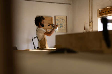 A young couple of carpenter working together in a small wood laboratory using a drill machine for timber. Couple crafting new home furniture in a carpentry workshop. young entrepreneurs concept A young couple of carpenter working together in a small wood laboratory using a drill machine for timber. Couple crafting new home furniture in a carpentry workshop. young entrepreneurs concept