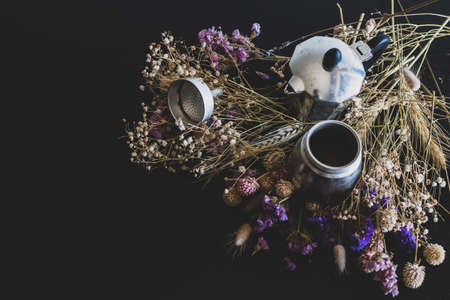 Coffee making concept. Ingredients for making moka coffee. Moka pot with coffee on dark background with a lot of colorful flowers. The coffee is in a vintage aesthetic composition.の写真素材