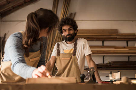 A young couple of carpenters working together in a small carpentry workshop designing a new home...