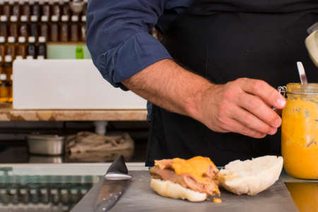 top view closeup of hispanic male hands cutting and making a bread sandwiches with pork meat with sauce, traditional bifana, and empanadas, traditional tasty latin food. Process to make sandwiches.の写真素材