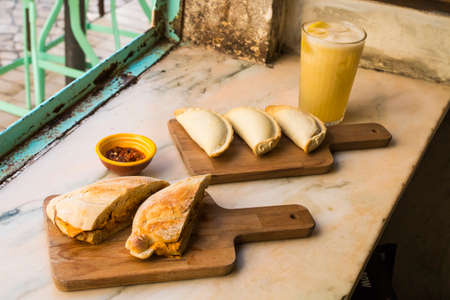Traditional baked Argentine empanadas savory pastries with meat and a sandwich beef stuffing with tasty bread against wooden background. Healthy food served with a ice lemon tea, fresh and homemade.の写真素材