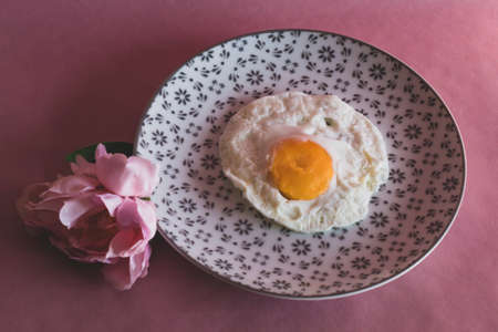 Homemade meal, Organic tasty cooked eggs for healthy breakfast on pink background, fancy ceramic plates, and flowers in a vintage artistic composition. Simple food composition.の写真素材
